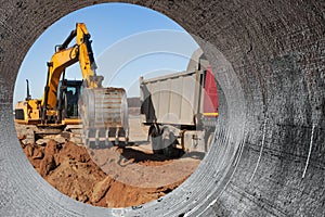 An excavator loads soil or sand into a dump truck. Pit development. Earthworks with the help of heavy construction equipment