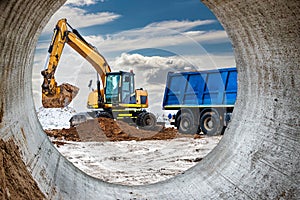 An excavator loads soil or sand into a dump truck. Pit development. Earthworks with the help of heavy construction equipment