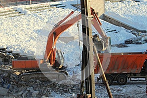 Excavator loads soil into a truck at a construction site in winter in Russia