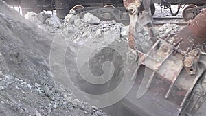 The excavator loads the stones into the cars.