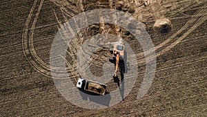 Excavator loads truck aerial view from above with drone
