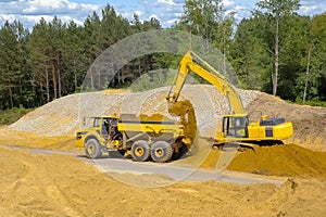The excavator loads a truck body with sand