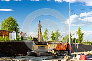 Excavator loads truck, construction bypass road