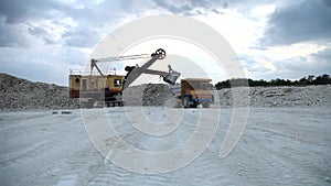 Excavator loads a truck rock in the quarry