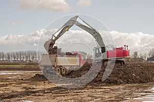 Excavator loads truck with soil