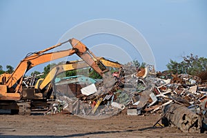 Excavator magnet lifting steel scraps from recycling materials pile at scrap yard in recycling factory. Excavator with electro and