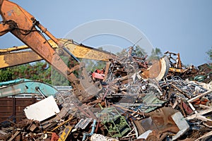 Excavator magnet lifting steel scraps from recycling materials pile at scrap yard in recycling factory. Excavator with electro and