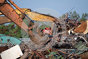 Excavator magnet lifting steel scraps from recycling materials pile at scrap yard in recycling factory. Excavator with electro and