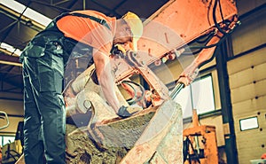 Excavator Mechanic Taking Closer Look Into the Crawler Bucket