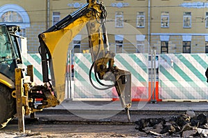 An excavator-mounted hydraulic jackhammer being used to break up concrete