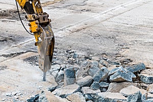 Excavator mounted hydraulic jackhammer at breaking concrete area