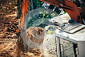 Excavator moving earth on construction site. Close-up of bucket full of earth