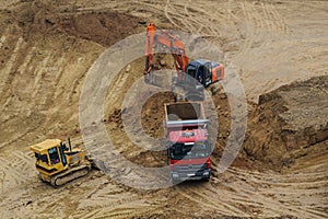 Excavator moving earth and unloading into a dumper truck