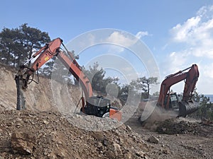 Excavator moving soil with lots of dust during excavation works on the rocky soils. Heavy machinery at earthmoving