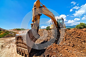 Excavator moving soil and sand on road construction site