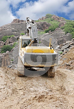 An excavator moving on top level of a granite mine