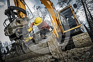 Excavator Operator Works at a Construction Site in Muddy Terrain During Daylight