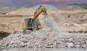 Excavator placing blasted stones in the bottom of an excavation