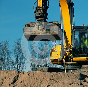 Excavator in the process of leveling the slope of the road