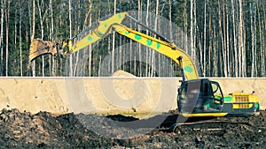 Excavator in the process of leveling the slope of the road