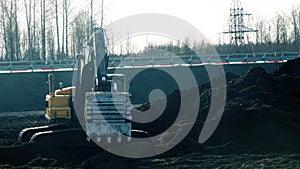 Excavator in the process of leveling the slope of the road