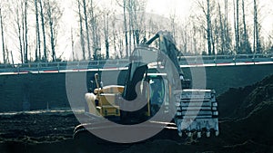 Excavator in the process of leveling the slope of the road