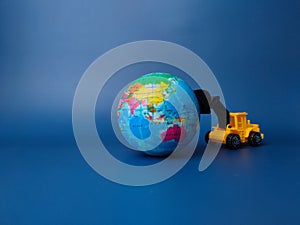 Excavator pushing earth globe with gavel on blue background