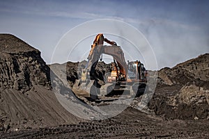 Excavator in a quarry digging rubble stone