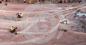 Excavator in a quarry extracting and moving stone for its transformation, top view