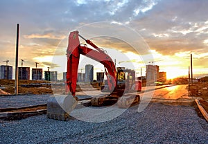 Excavator during road work at construction site on awesome sunset background. Screeding gravel for laying asphalt and borders