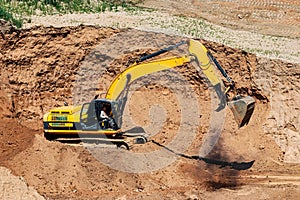 An excavator in a sand pit loads a dump truck with sand. Extraction of sand in an open pit. natural building materials