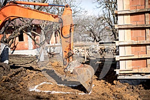Excavator scoop on construction site, digging and loading dumper trucks.