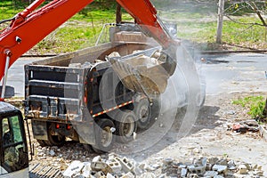 Excavator scoop truck loading a construction waste into reinforced concrete recycling garbage