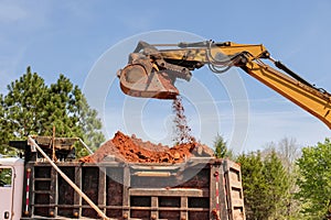 The excavator is scooping up the soil in dumper truck is waiting to be loaded.