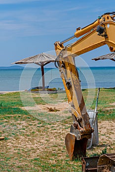 Excavator on the sea beach, against the backdrop of the beach