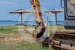 Excavator on the sea beach, against the backdrop of the beach