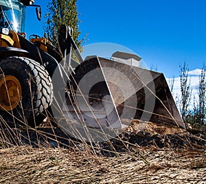 Excavator shovel clearing dirt and tree roads from a natural disaster. A big excavator making some maintenance works