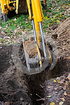 The excavator shovels earth with clay from the pit with a bucket for the construction of a septic tank. Ground work of the machine