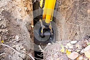 The excavator shovels the earth from the pit under the septic tank with a bucket. Working the machine with the ground