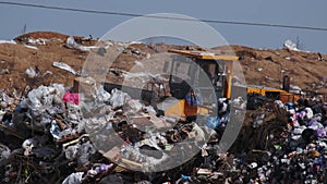 An excavator shovels garbage at a landfill. Vulture birds fly over the garbage. Ecological problems