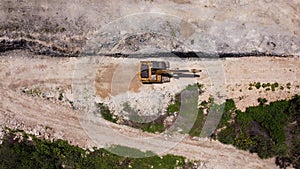 An excavator travelling on unpaved road corner aerial photo