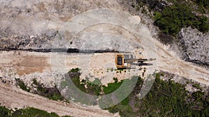 An excavator travelling on a zigzag open land with some green left around it photo