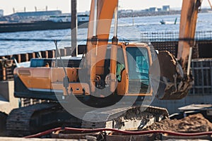 Excavator unloading sand into the dump truck on the construction site, excavating and working during road works, backhoe and