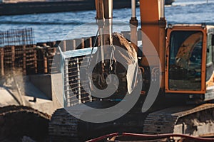 Excavator unloading sand into the dump truck on the construction site, excavating and working during road works, backhoe and