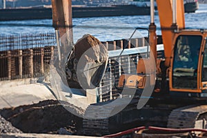 Excavator unloading sand into the dump truck on the construction site, excavating and working during road works, backhoe and