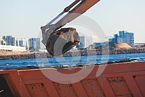 Excavator unloading sand into the dump truck on the construction site, excavating and working during road works, backhoe and