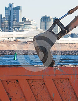 Excavator unloading sand into the dump truck on the construction site, excavating and working during road works, backhoe and