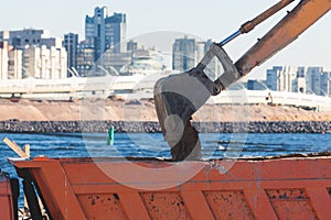 Excavator unloading sand into the dump truck on the construction site, excavating and working during road works, backhoe and