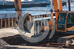 Excavator unloading sand into the dump truck on the construction site, excavating and working during road works, backhoe and