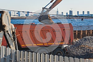 Excavator unloading sand into the dump truck on the construction site, excavating and working during road works, backhoe and